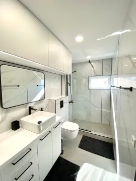Modernly equipped bathroom with white elements and marble tiles. - image 4