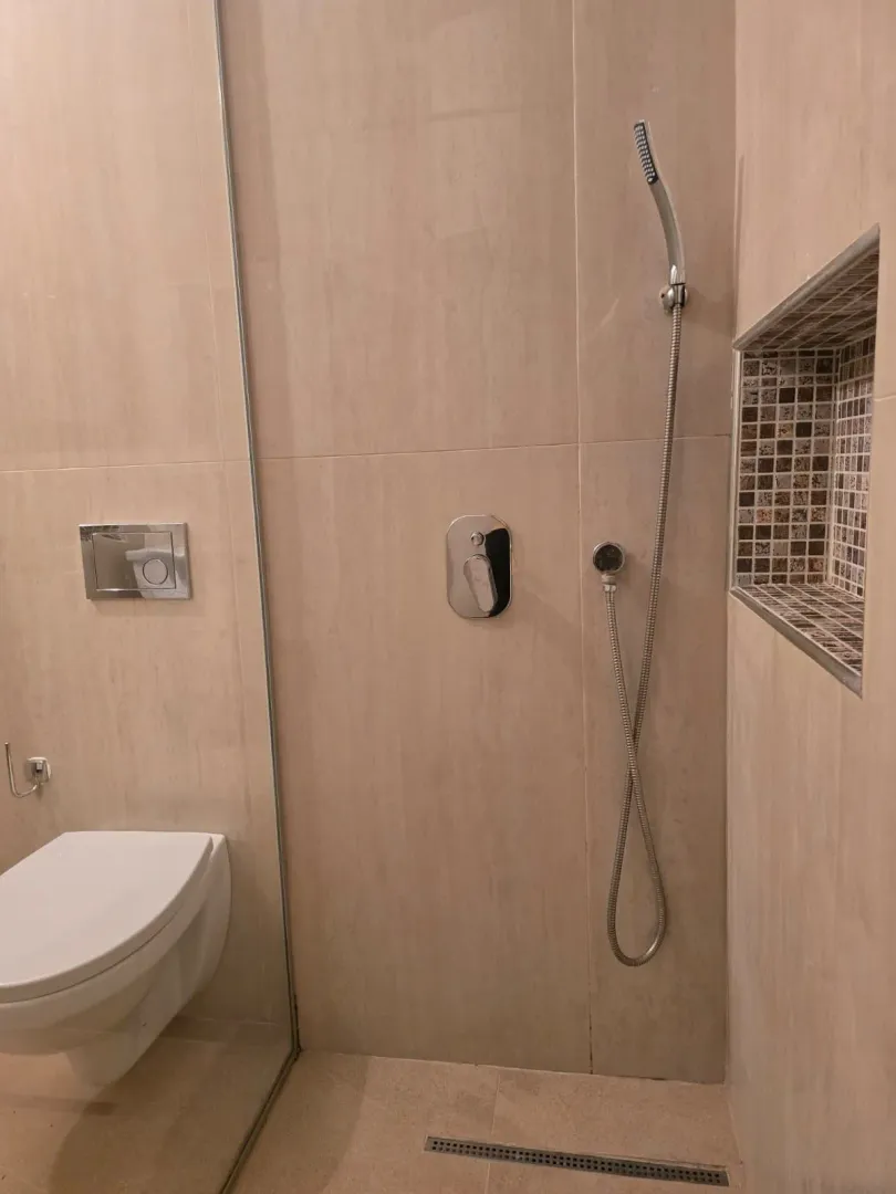 Moderne kupatilo sa tuš kabinom i ugradnom sanitarijom u bež tonovima.