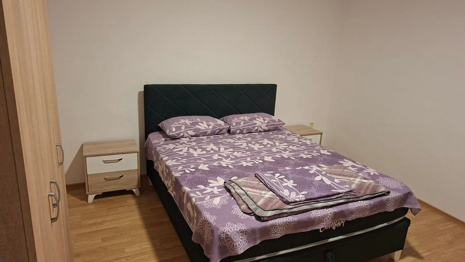 Namještena spavaća soba sa bračnim krevetom, noćnim stočićima i garderoberom.
