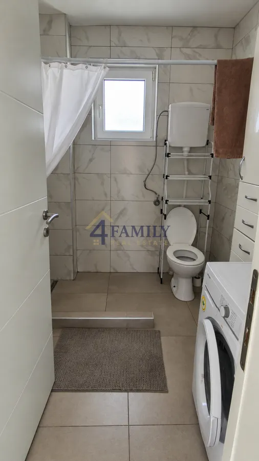 Small bathroom with a shower, toilet, and washing machine.