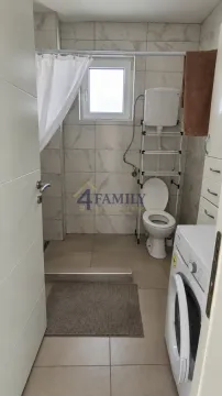 Small bathroom with a shower, toilet, and washing machine. - image 11