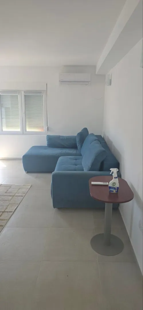 Dnevna soba sa plavom ugaonom garniturom i malim stočićem.