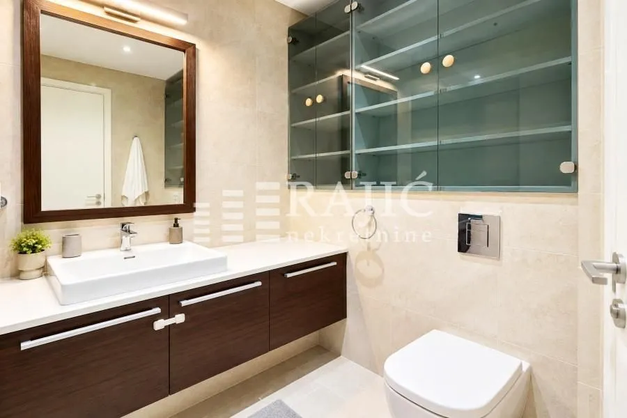Modernly equipped bathroom with a washbasin, mirror, and toilet.