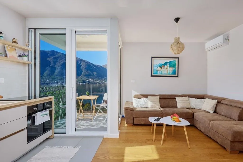 Living room with sofa, kitchen and access to the balcony with mountain views.