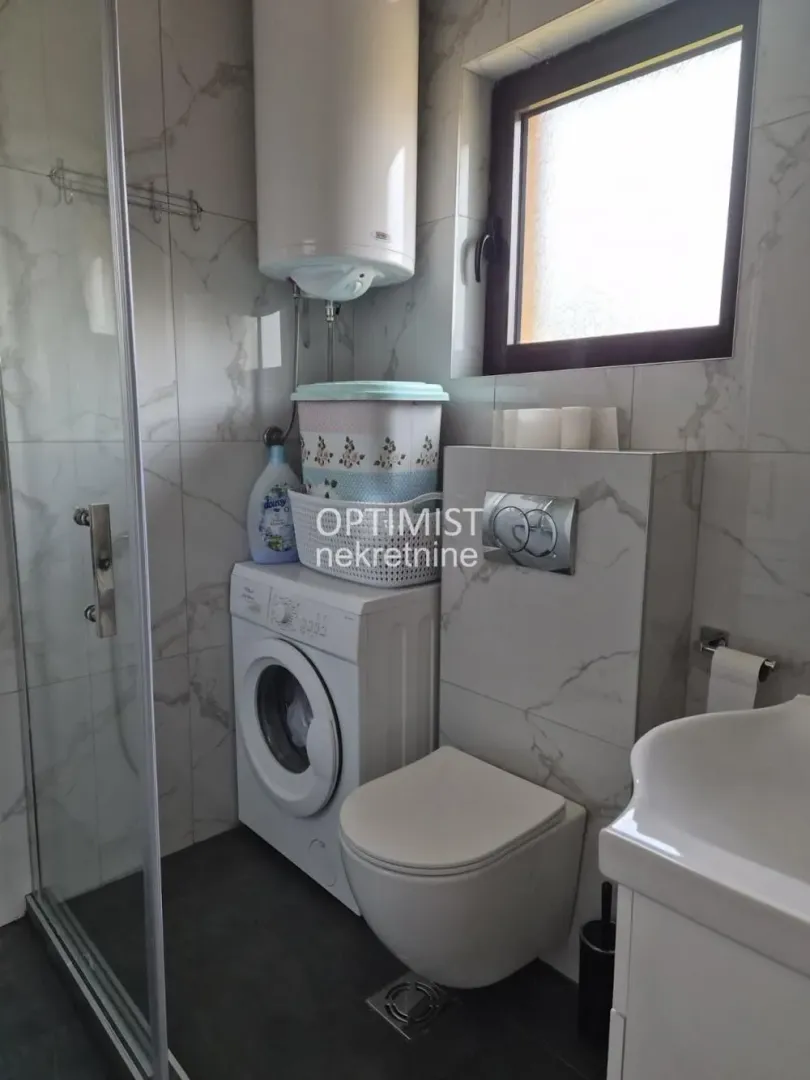 Kupatilo opremljeno tuš kabinom, wc šoljom, umivaonikom i veš mašinom.