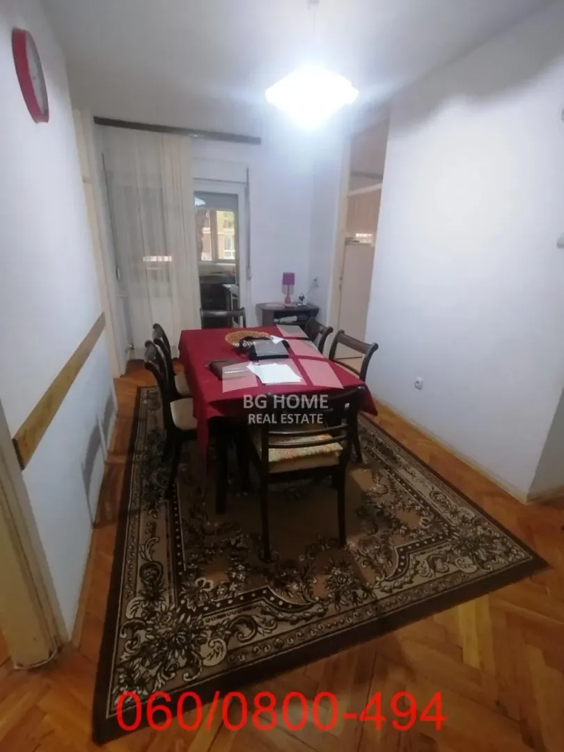 Trpezarija sa stolom, stolicama i tepihom na podu.