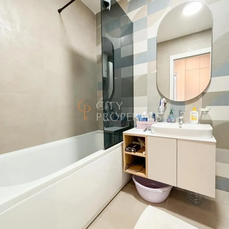Bathroom with a bathtub, washbasin, and mirror.