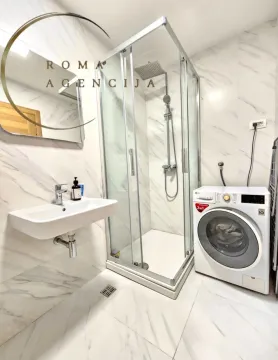 Modern bathroom equipped with a shower cabin, washbasin, and washing machine. - image 7