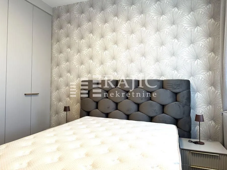 Modern bedroom with a double bed, wardrobe, and patterned wallpaper.