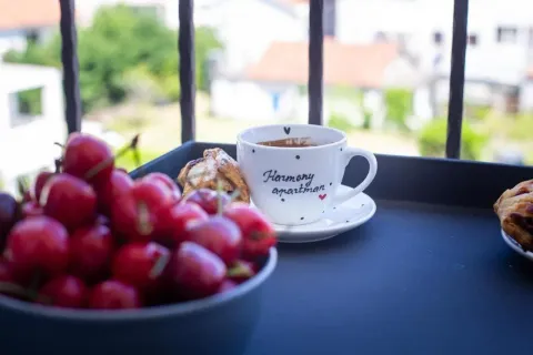A cup of coffee, fresh cherries and pastry on a table on the balcony. - image 15