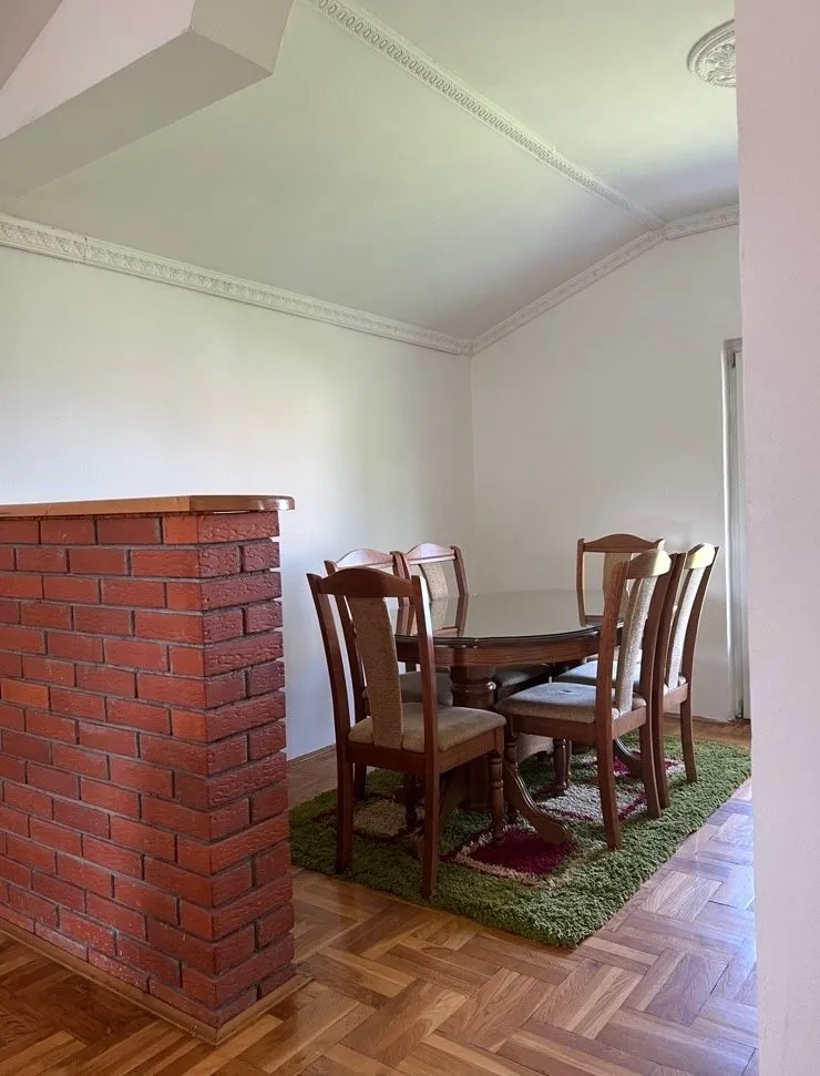Dining room with a wooden table, chairs, and parquet flooring.