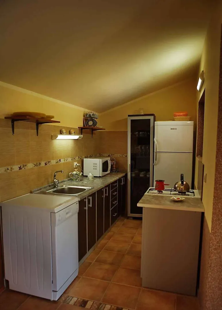 Praktična kuhinja sa kuhinjskim elementima i aparatima.