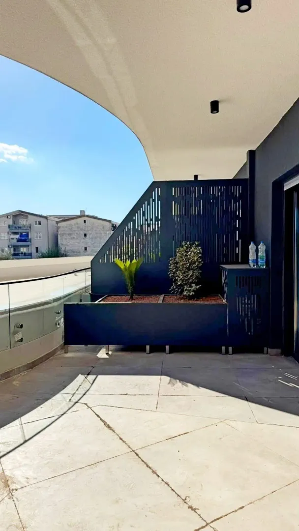Spacious modern terrace with planters and a view of surrounding buildings.