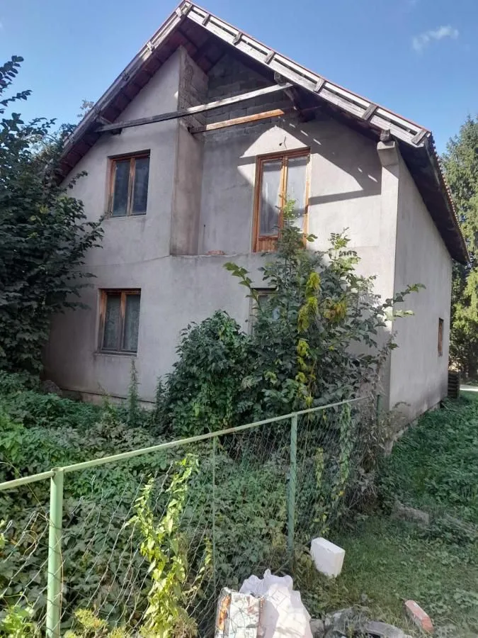 Exterior view of an older house with a yard and greenery.