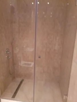 Moderna tuš kabina obložena bež pločicama sa staklenom pregradom. - image 6
