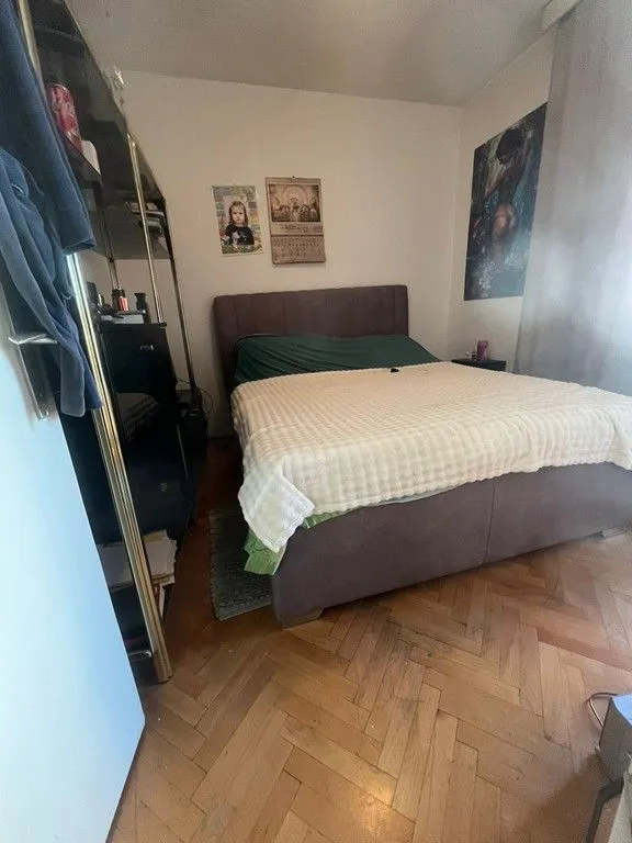Namještena spavaća soba sa bračnim krevetom i parketom.