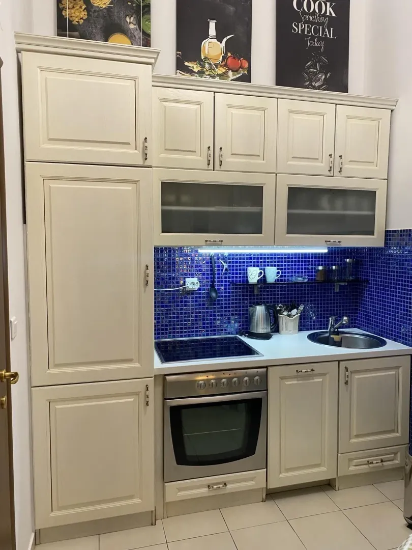 Kitchen with light cabinets and blue tiles.