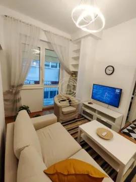 Small living room furnished with a sofa, TV, and access to the balcony. - image 6