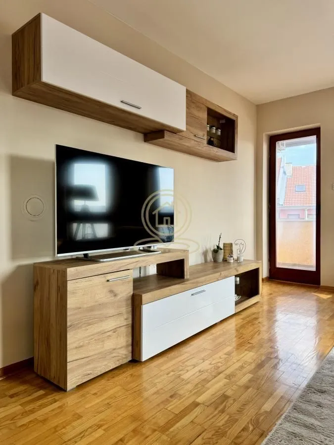 Living room with wooden furniture, TV, and access to the terrace.