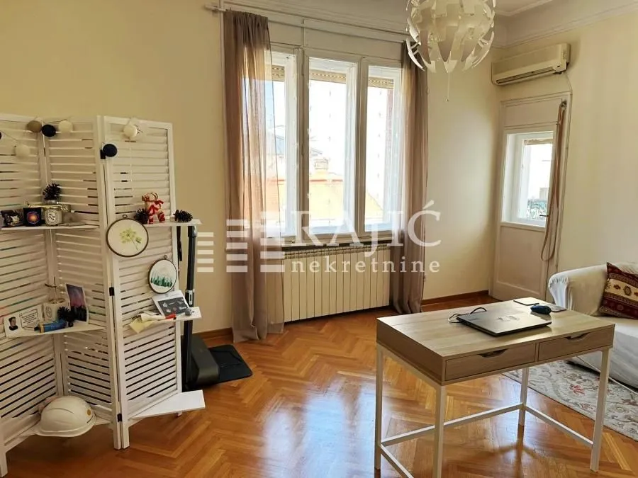 Living room with a desk and parquet flooring.