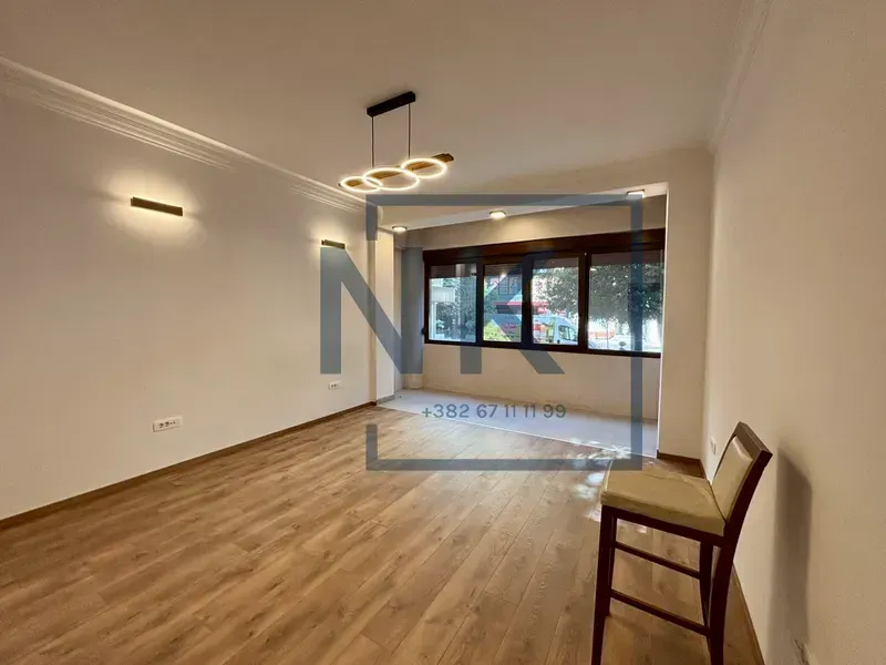 Empty living room with wooden flooring and modern lighting.