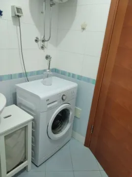 Dio kupatila sa veš mašinom i drvenim vratima. - image 4