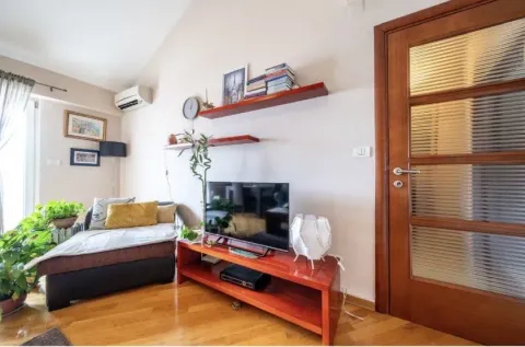 Living room with a sofa, TV unit, and wooden flooring. - image 5