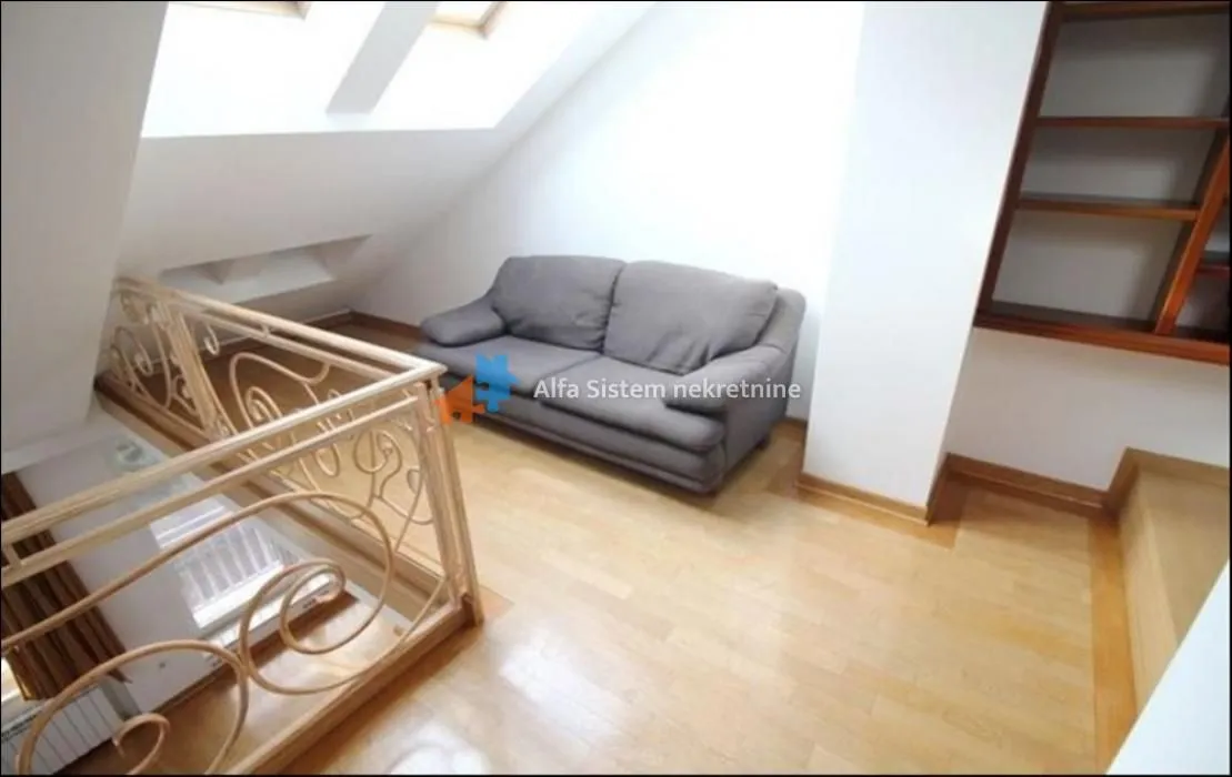 Attic space with a sofa and stairs.