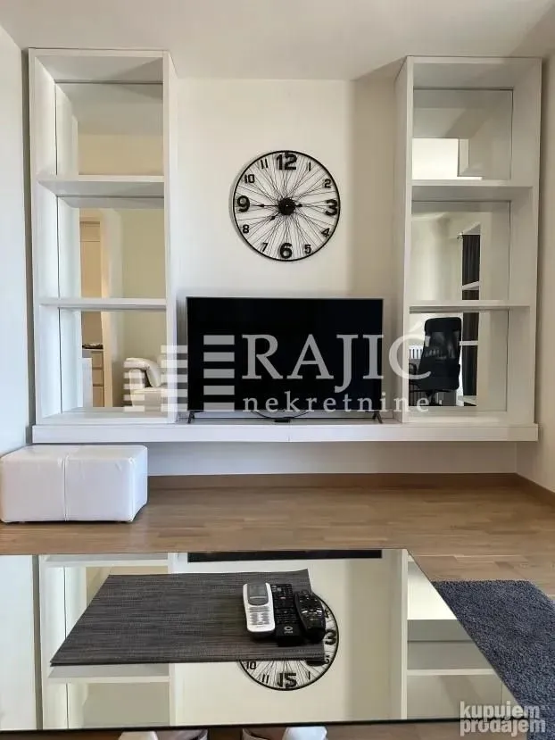 Living room with white wall units, a television, and a decorative wall clock.
