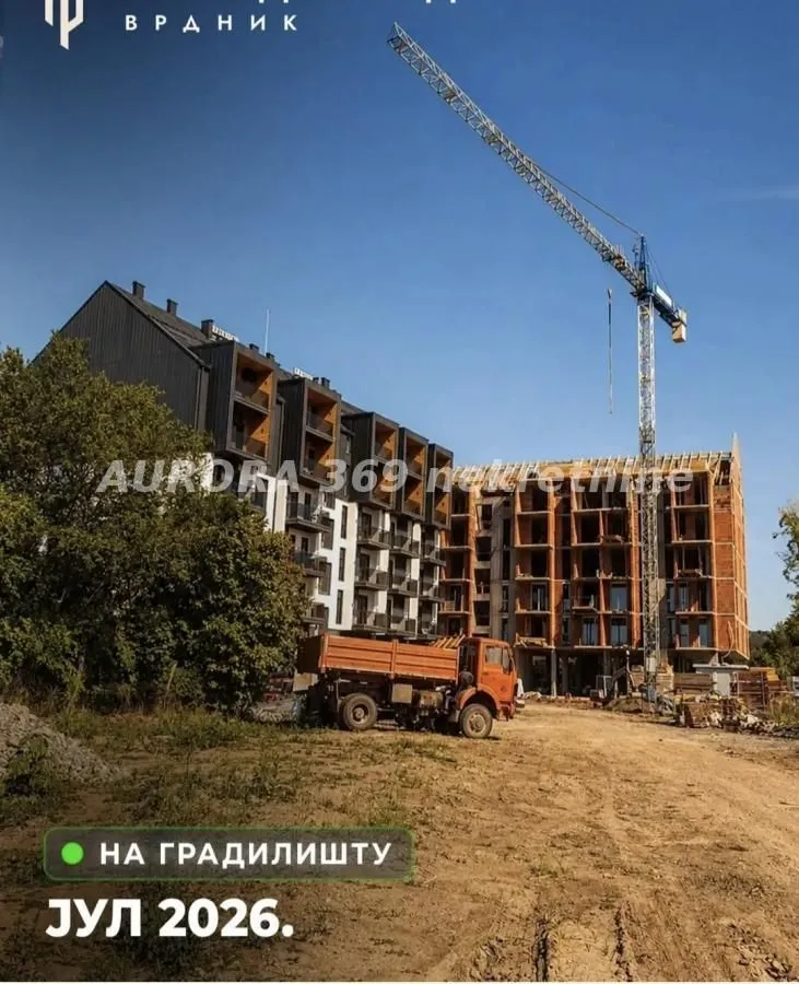 Pogled na zgradu u izgradnji sa građevinskim kranom i kamionom.