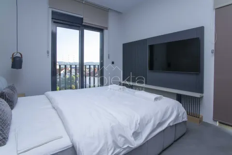Moderna spavaća soba sa bračnim krevetom, televizorom na zidu i balkonskim vratima. - image 2