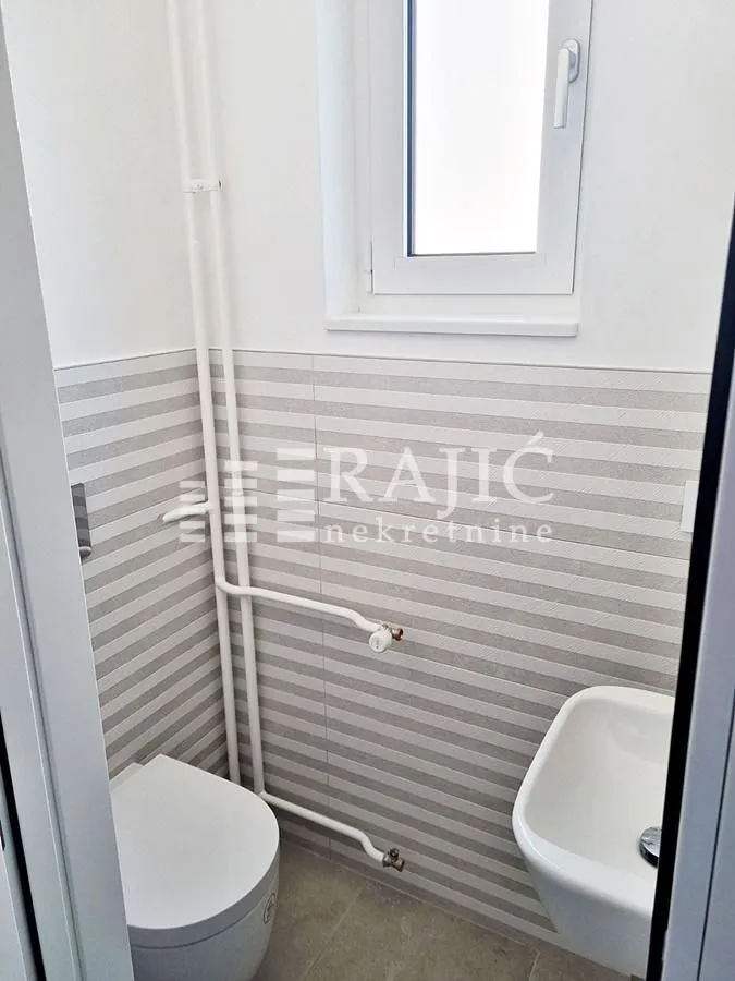 Small bathroom with a toilet, washbasin, and white wall tiles.