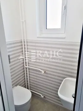 Small bathroom with a toilet, washbasin, and white wall tiles. - image 17