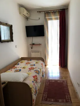 Small bedroom with a single bed, wall-mounted TV, and balcony access. - image 12