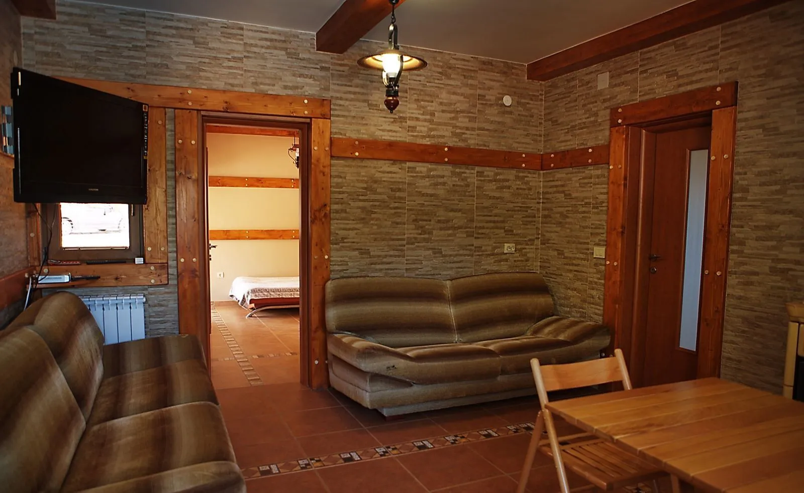 Dnevna soba sa kamenim zidovima, drvenim detaljima i garniturom za sjedenje.