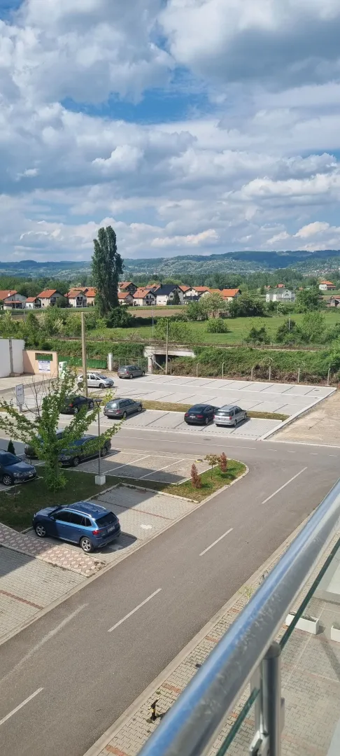 Pogled sa terase na parking i okolni pejzaž sa brdima.