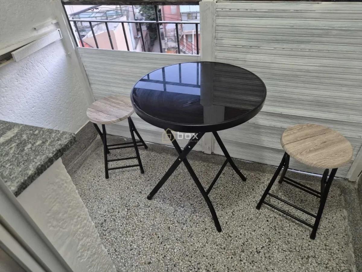 Manji zatvoreni balkon sa okruglim stolom i dve stolice.