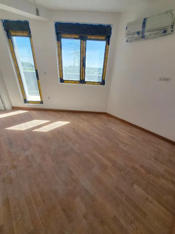Prazna prostorija sa parketom i montiranim klima uređajem.