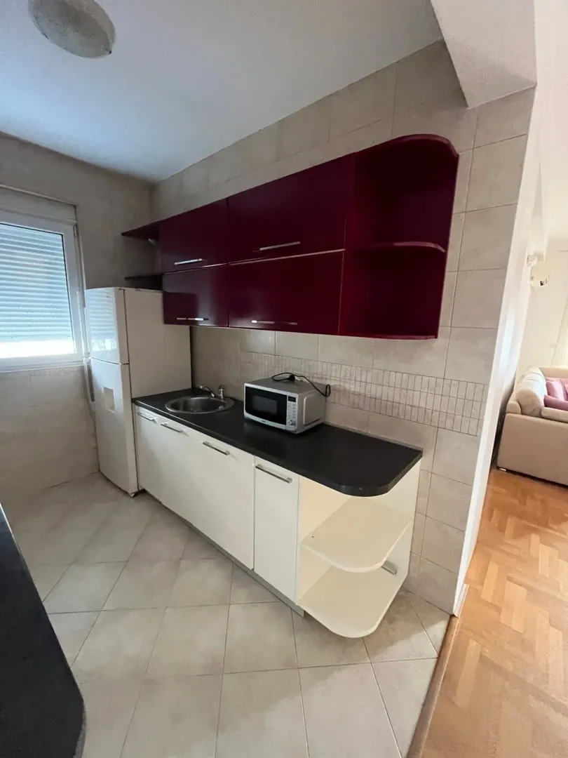 Smaller kitchen with white and maroon cabinets.