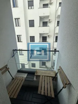 Small furnished balcony with wooden chairs and a view of the neighboring building. - image 7