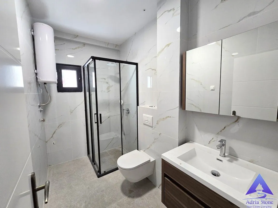Modernly equipped bathroom with a shower cabin, washbasin, and toilet.