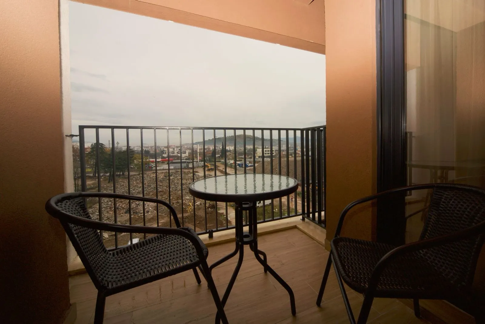 Covered balcony with a small table, chairs, and a city view.