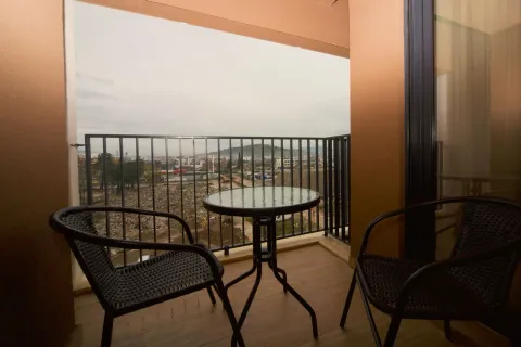 Covered balcony with a small table, chairs, and a city view. - image 9