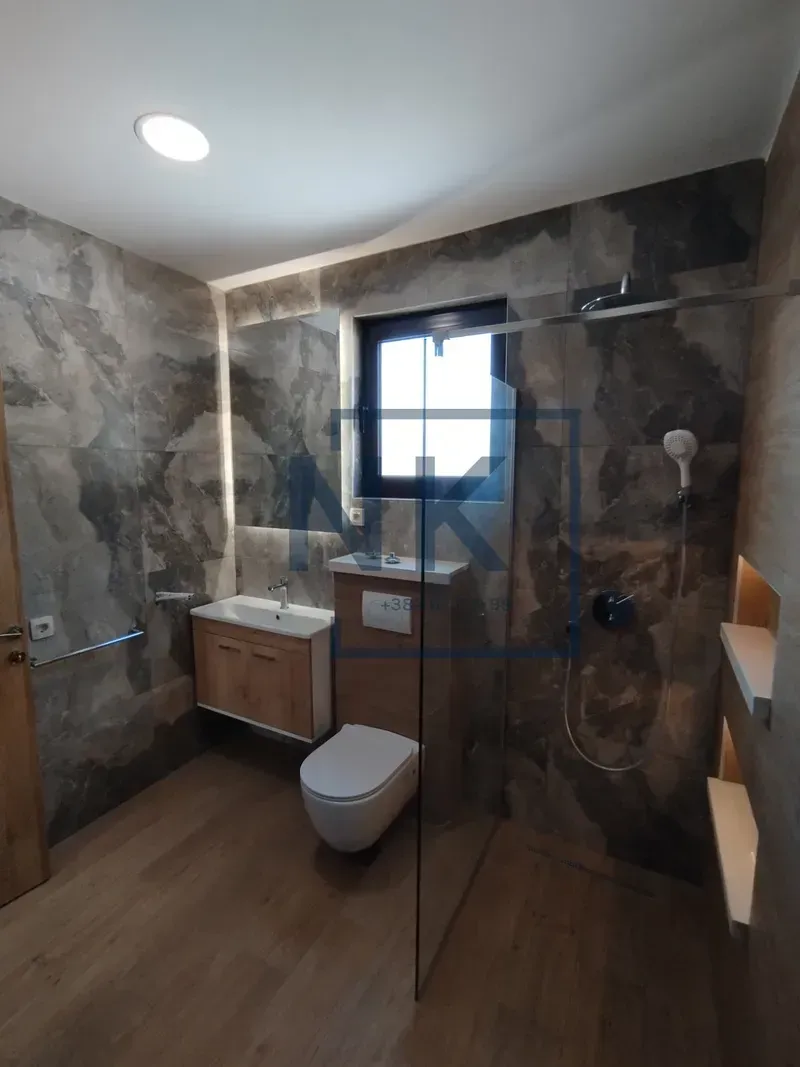 Modern bathroom with a walk-in shower, washbasin, and toilet.