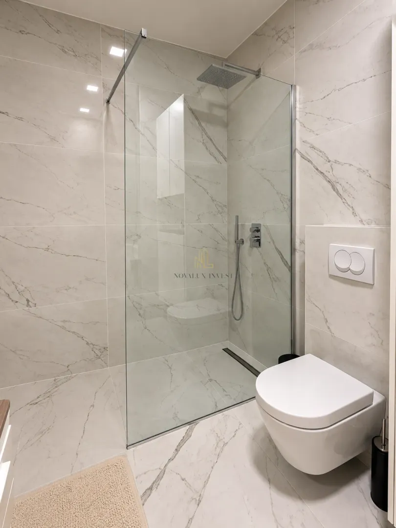 Moderne kupatilo sa tuš kabinom i ugradnom wc šoljom.