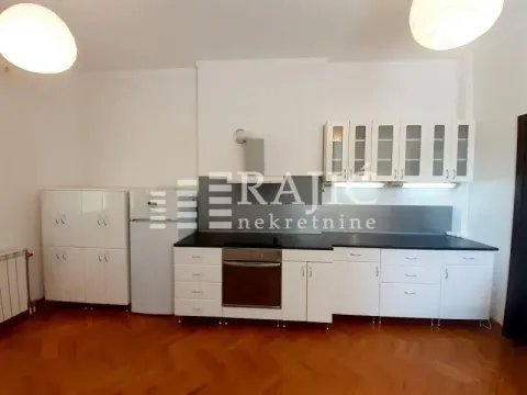 Moderna kuhinja sa belim elementima i tamnom radnom površinom. - image 15