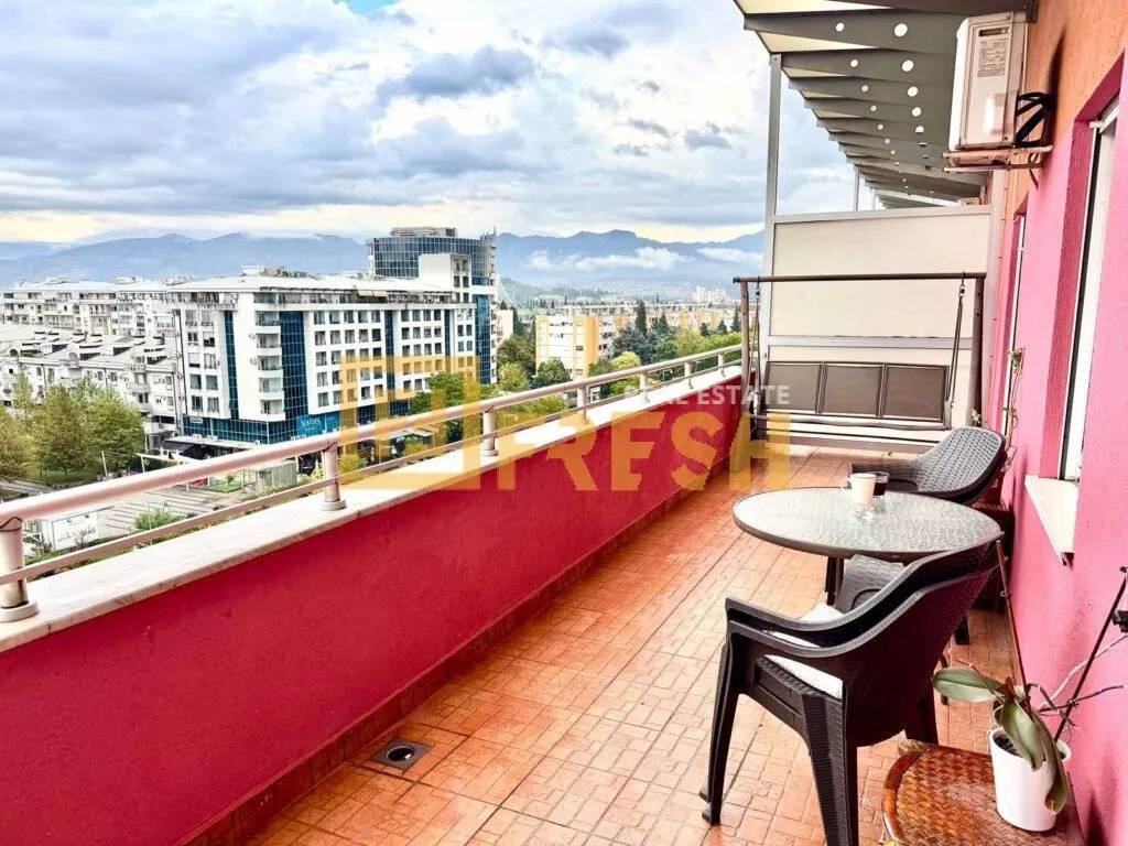 Spacious terrace with outdoor seating and a view of the city and mountains.