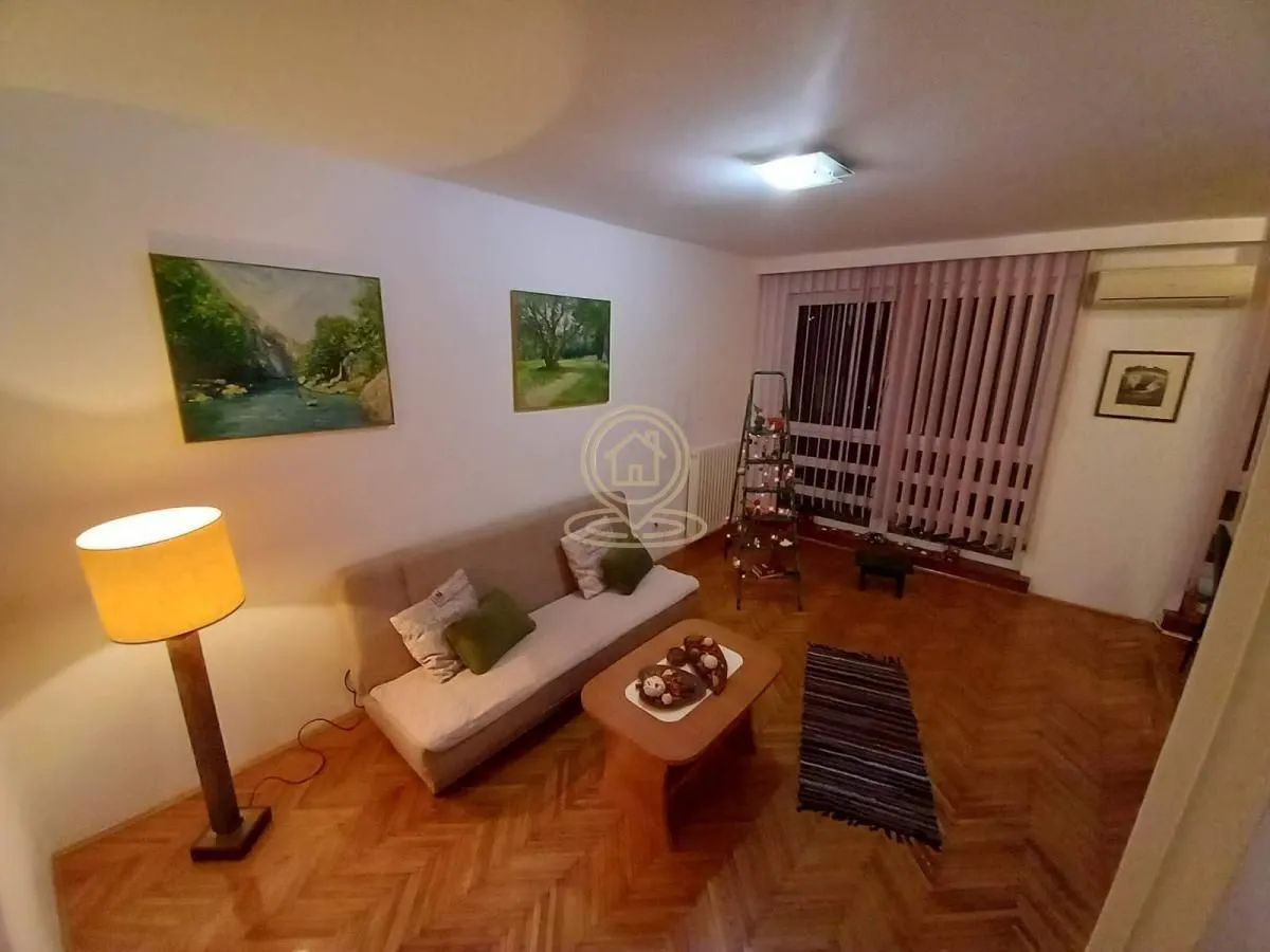 Living room with a sofa, coffee table and paintings on the wall.