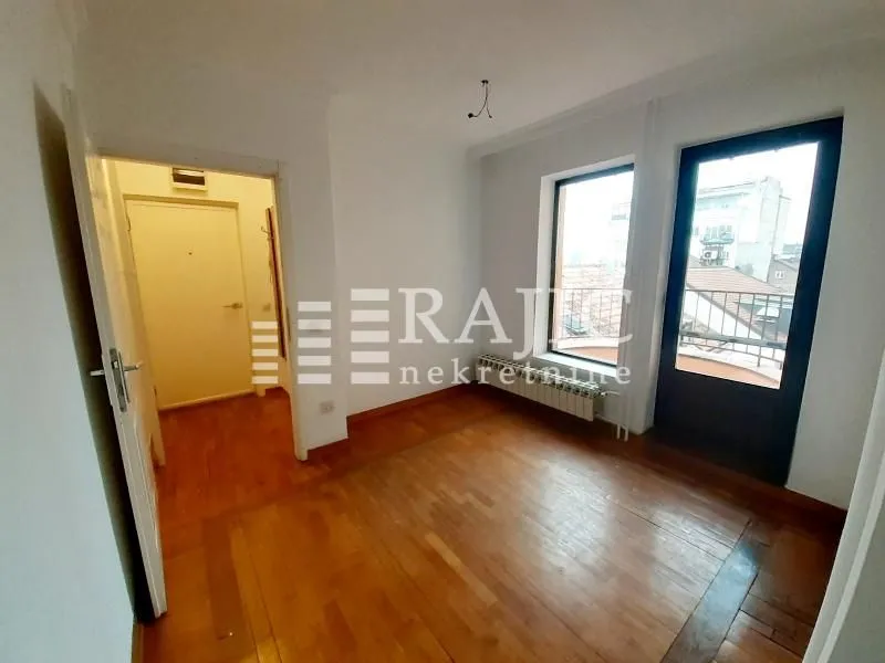 Empty room with parquet flooring and balcony access.
