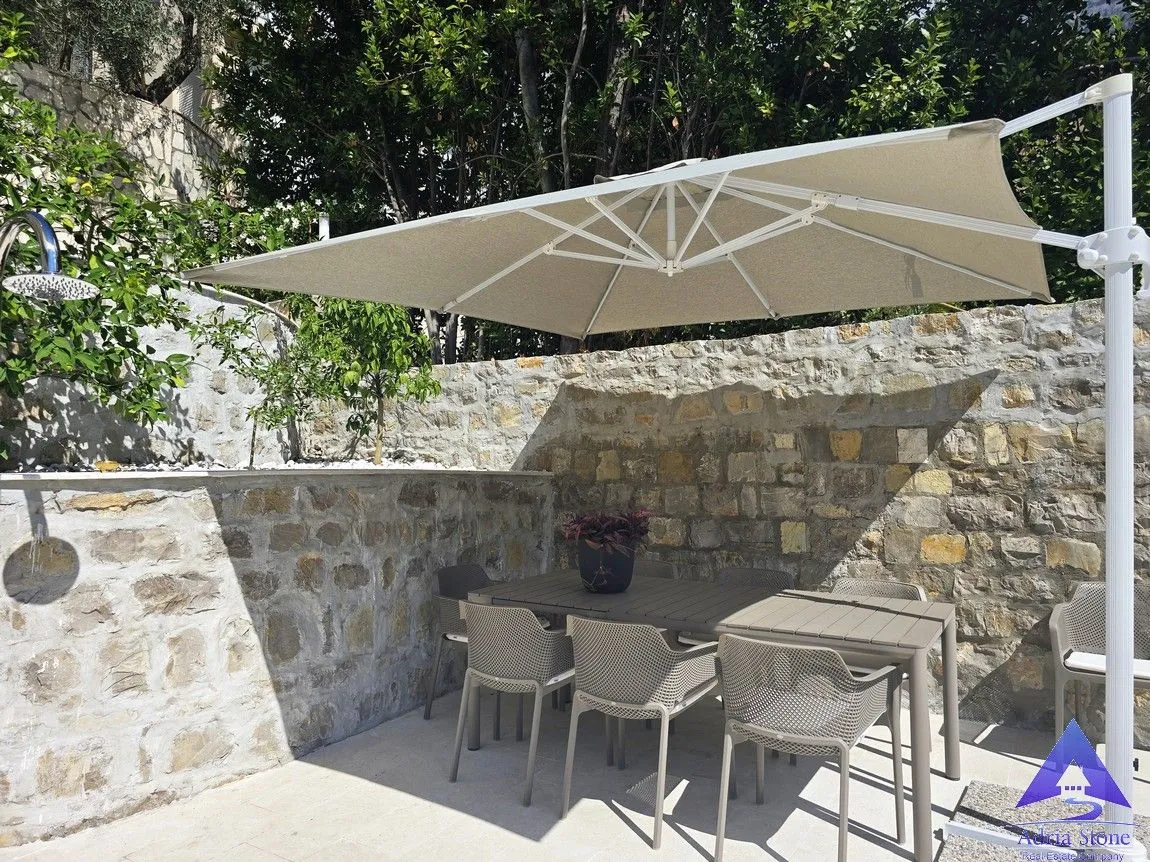 Terasa sa garniturom za sjedenje i velikim suncobranom u dvorištu.